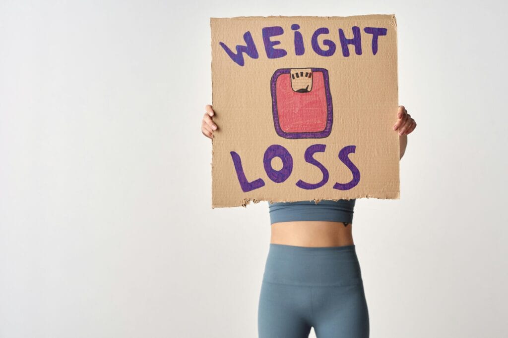 weight-loss-surgery Person holding 'weight loss' sign showing weight loss after surgery and what is bariatric surgery.